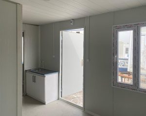 Yaşam konteyneri iç mekanı, mutfak tezgahı ve lavabo ile açık kapıdan dış görünüm